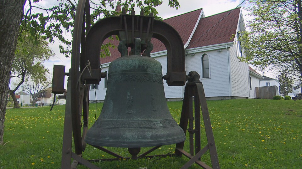 Une cloche d'église installée sur le gazon derrière le musée.