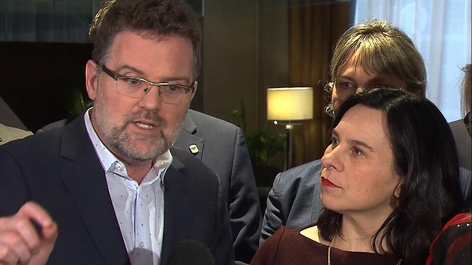 Un homme et une femme debout dans une mêlée de presse.