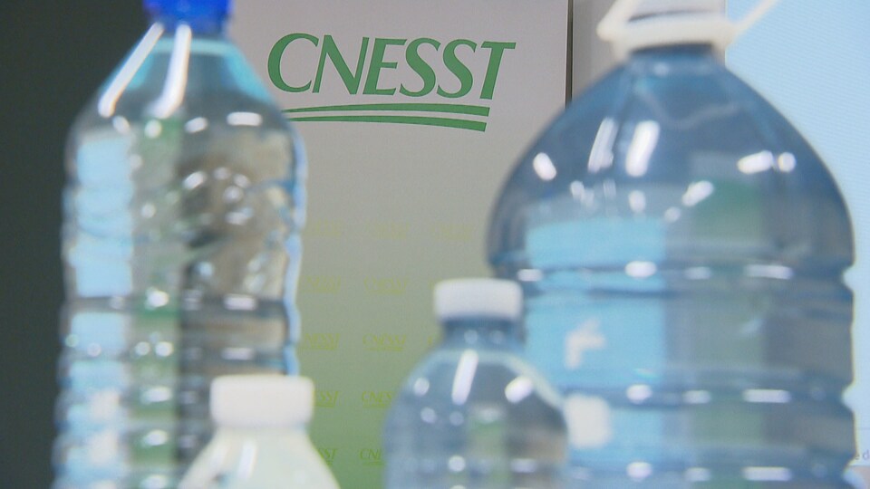 Des bouteilles d'eau devant le logo de la CNESST.