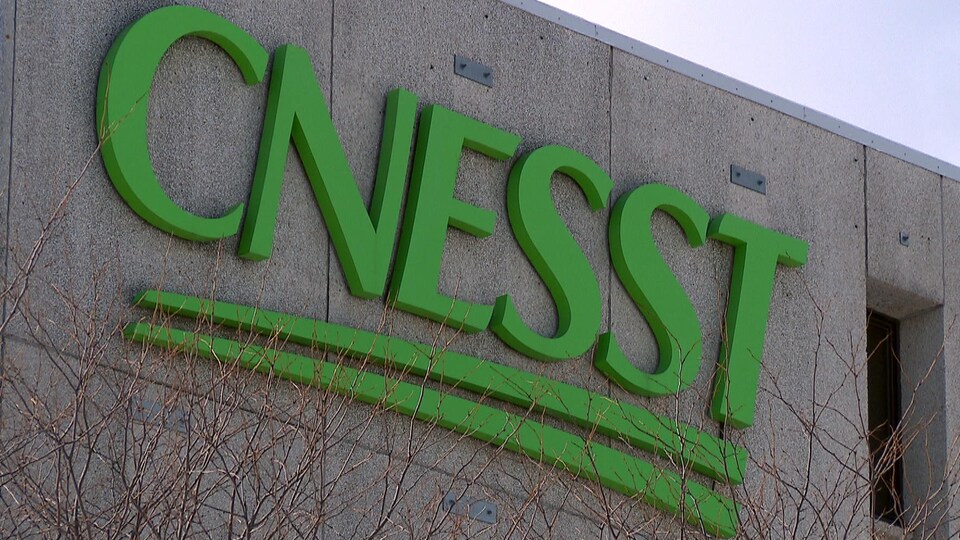 Plan rapproché du logo qui orne le siège social de la Commission des normes, de l'équité, de la santé et de la sécurité du travail à Québec. Les lettres C N E S S T sont peintes en vert.