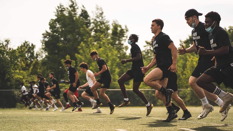 Des joueurs de football s'échauffent sur un terrain synthétique.
