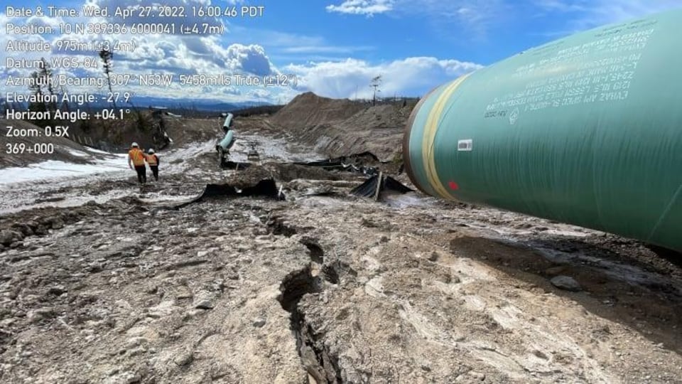 Un bout de pipeline surplombe un sol sec et dénudé traversé par une faille.