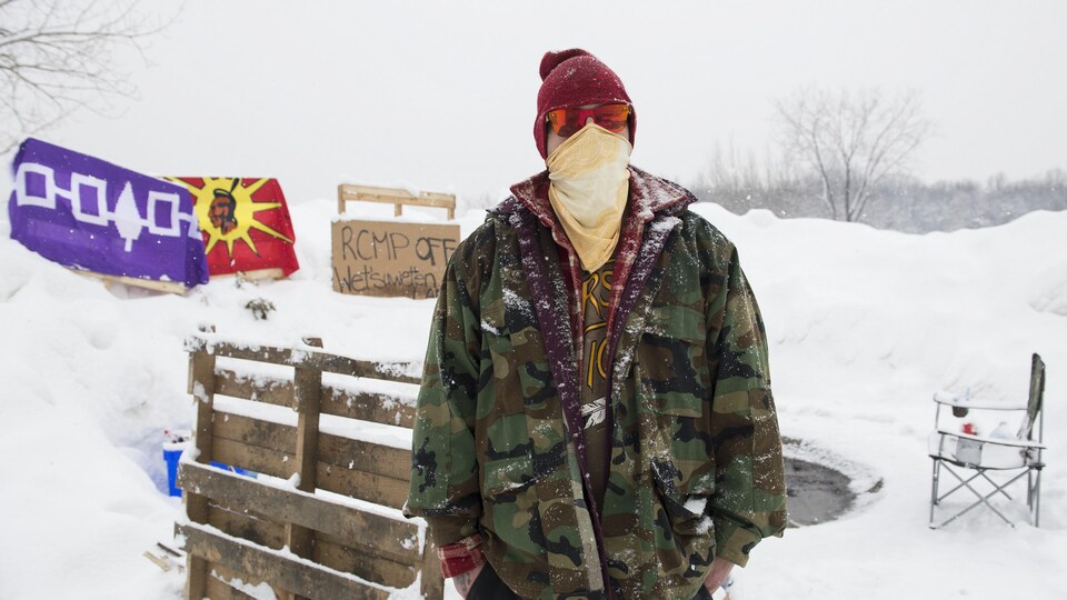 Un homme masqué se tient debout dans la neige et pose pour la caméra. 