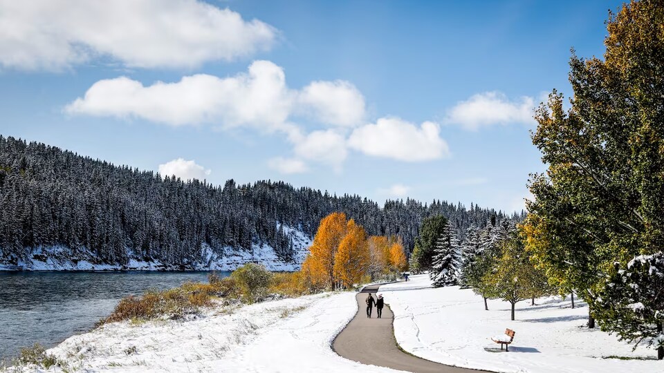 Deux personnes marchant au bord de la rivière Bow alors qu'il y a de la neige.