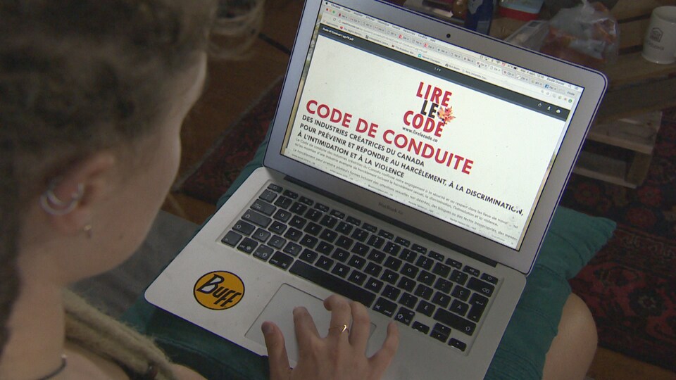 Une femme lit le code de conduite qui apparait à l'écran de son ordinateur portable.
