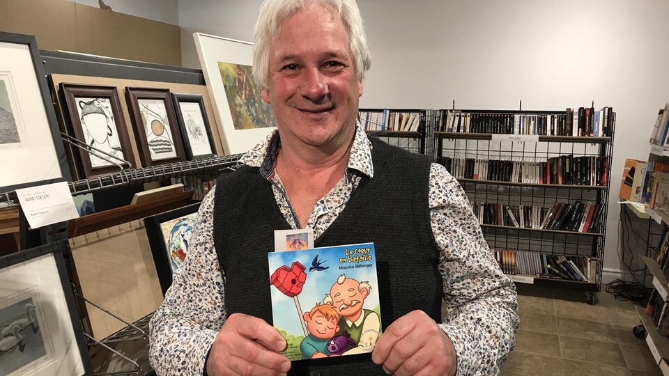 L'homme tient fièrement son oeuvre dans une librairie.
