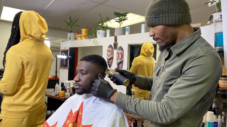 Stéphane Belinga, ou Belo, met la derni`re touche à une coiffure d'un jeune client.