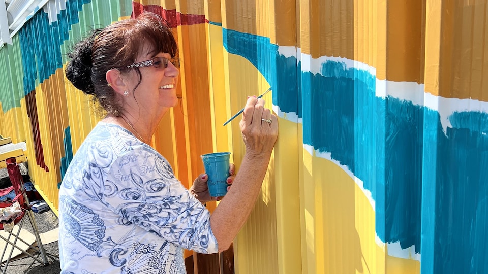 Une femme peinture une murale.
