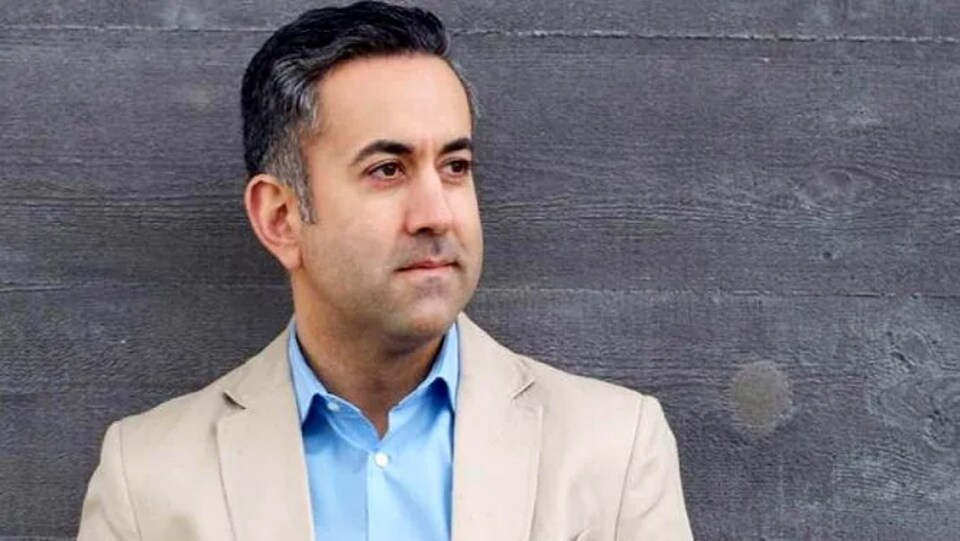 Portrait de Colin Basran près d'un mur en bois.