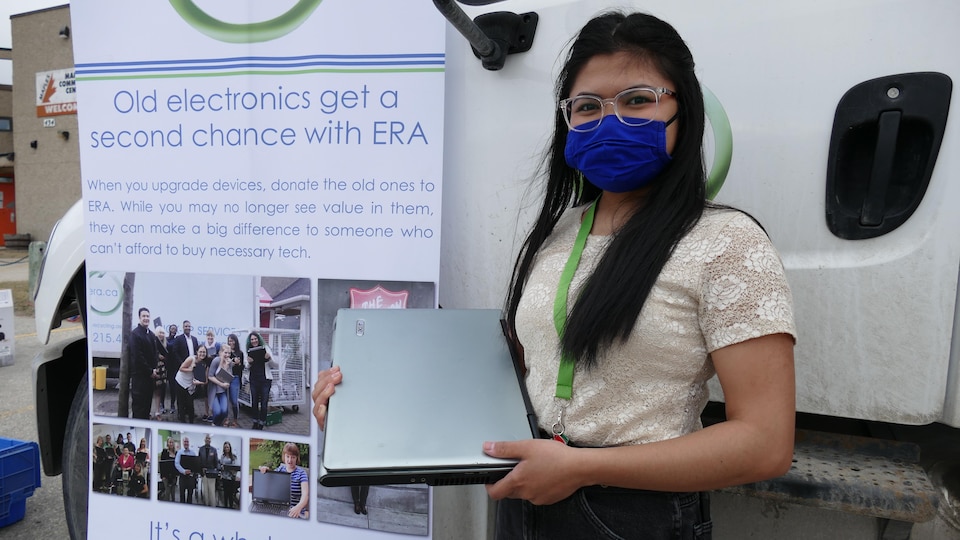 Aira Villanueva tient un ordinateur portable devant une affiche faisant la promotion du recyclage d'appareils électroniques.