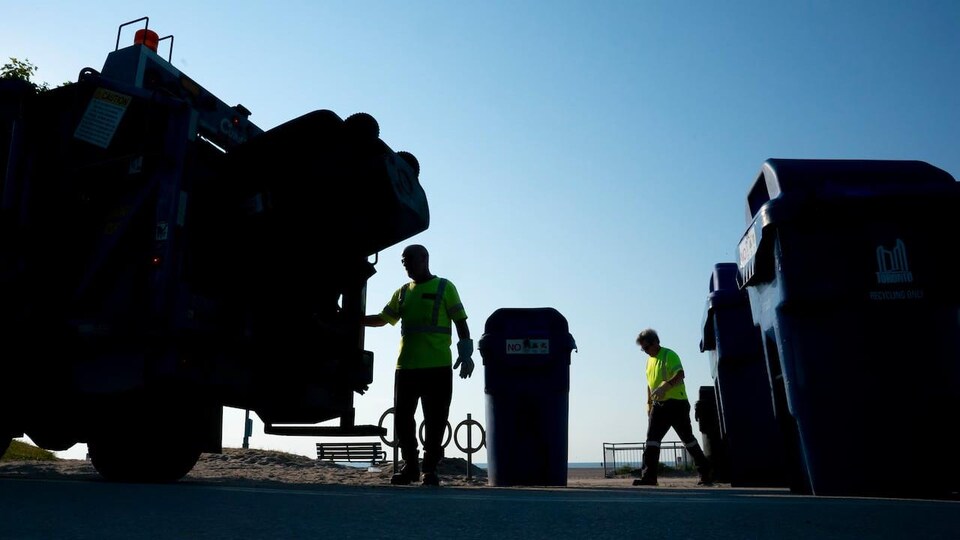 Un camion à ordure et deux employés