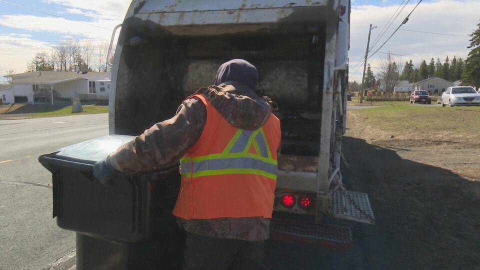 Un homme s'apprête à vider un bac d'ordures dans le camion.