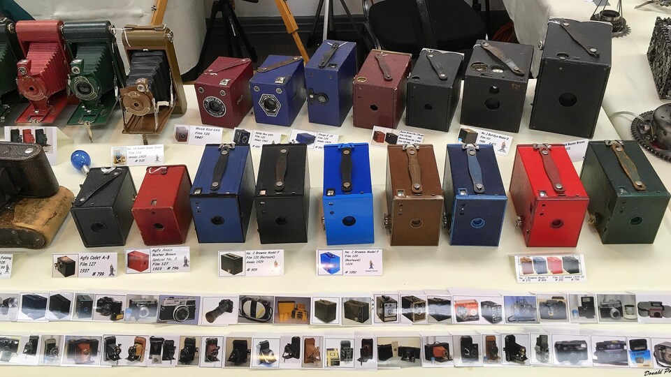 Des appareils photo anciens de type « boîte photographique » sont exposés sur une table.