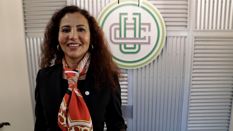 Saloua Zraida, directrice générale du Collège Universel, pose devant le logo de l'établissement.