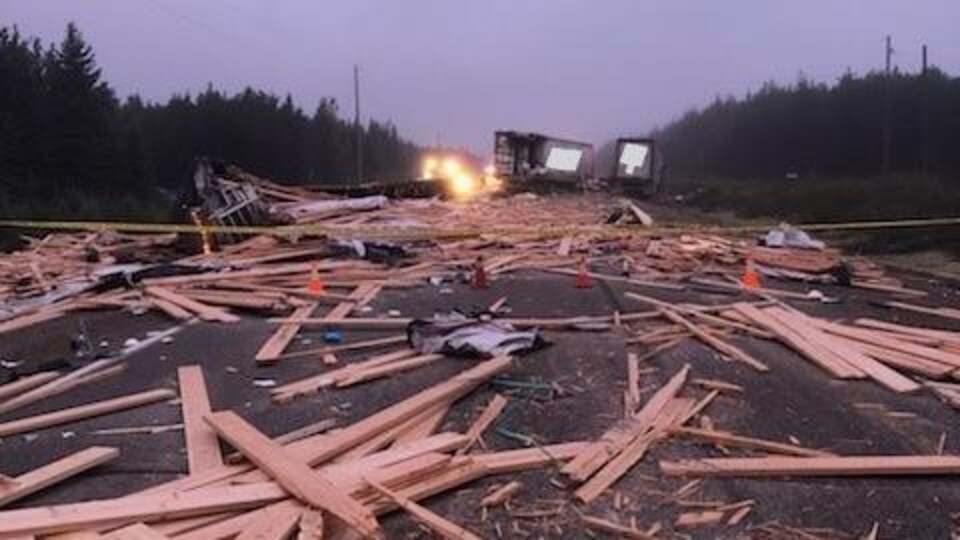 Des déchets de bois jonchent une route après une collision impliquant trois camions-remorques.