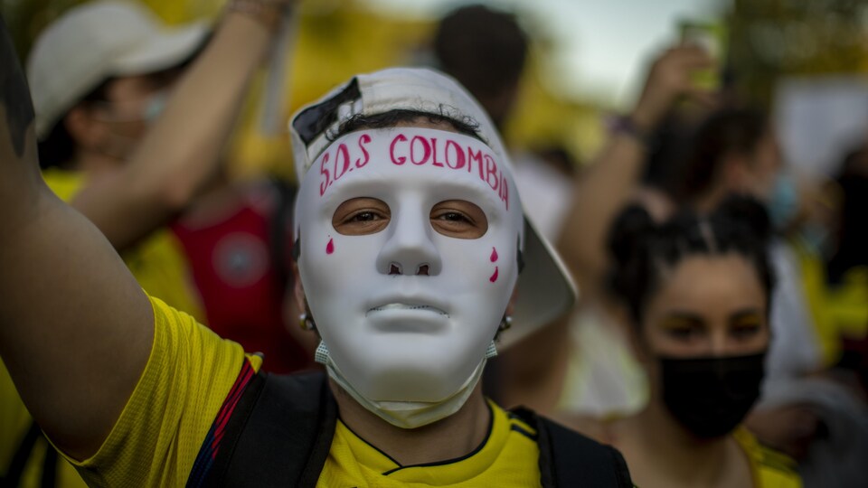 Un hombre usa una máscara con SOS Colombia escrito en ella. 