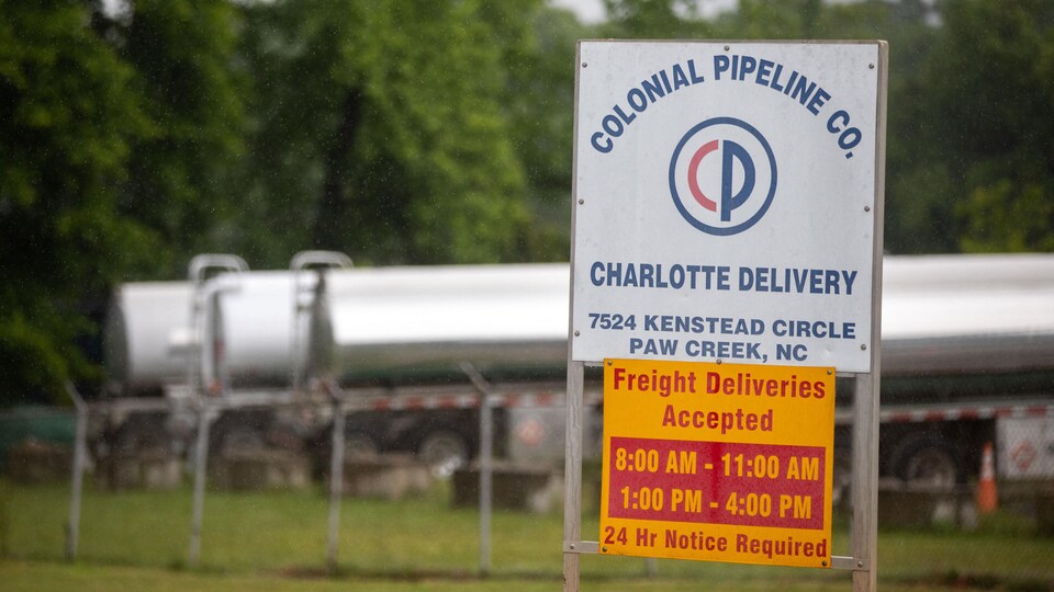 Des camions-citernes dans un lot adjacent à l'entrée d'un parc de réservoirs appartenant à Colonial Pipeline.