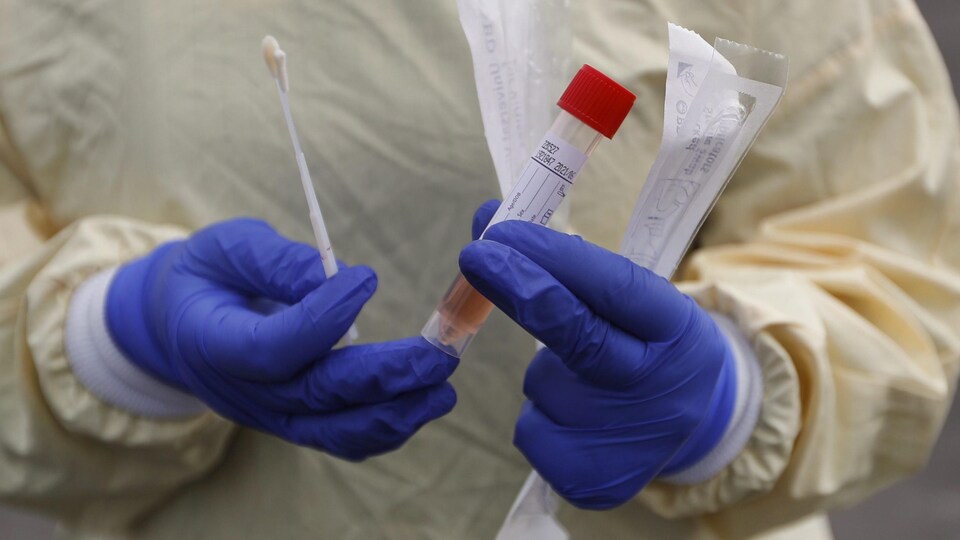 A nurse holds swabs and test tube to test people for COVID-19 at a drive through station set up in the parking lot of the Beaumont Hospital in Royal Oak, Mich., Monday, March 16, 2020. (AP Photo/Paul Sancya)