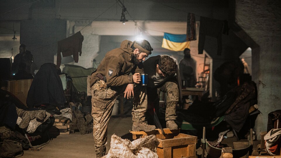Des combattants, dans les souterrains d'Azovstal, devant un drapeau ukrainien. 