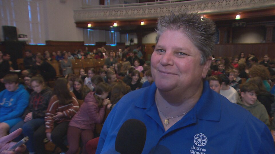 Brenda Comeau est interviewée devant des dizaines de jeunes dans une salle de spectacle.
