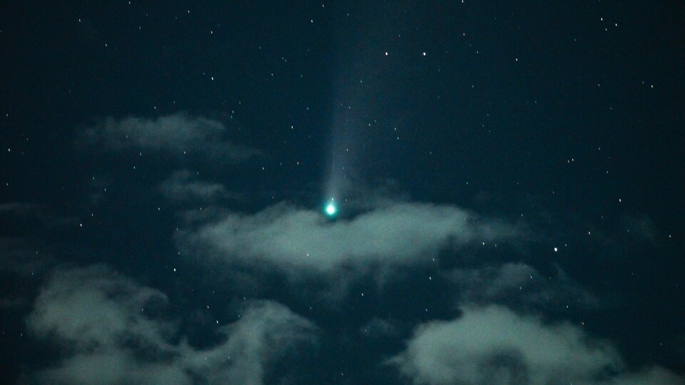 Une comète dans un ciel nuageux.