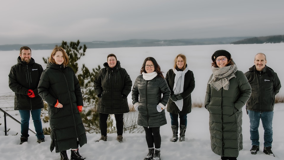Le comité organisateur du salon du livre de l'Abitibi-Témiscamingue avec de la neige et le lac Témiscamingue en arrière-plan.
