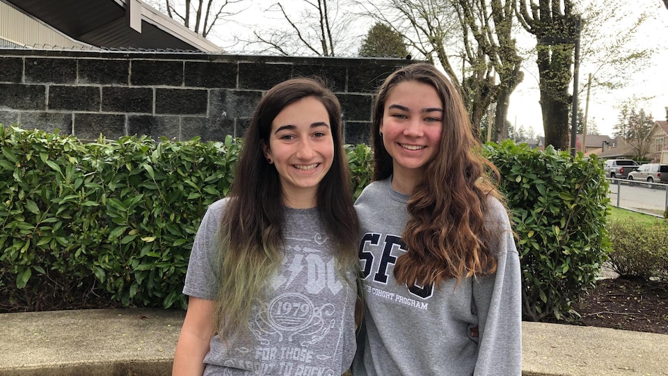 Deux jeunes femmes aux cheveux longs et souriantes posent pour la photo.