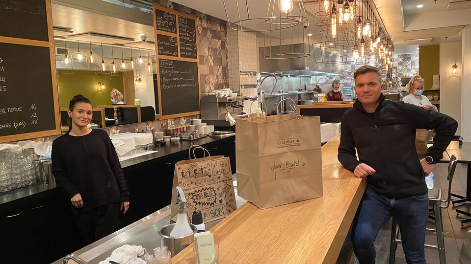 Une femme et un homme, séparé par un comptoir, dans un restaurant.