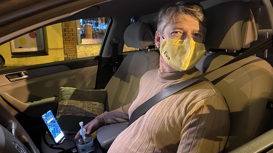 Un homme au volant de sa voiture, portant un masque jaune sur lequel on peut lire Eva. 