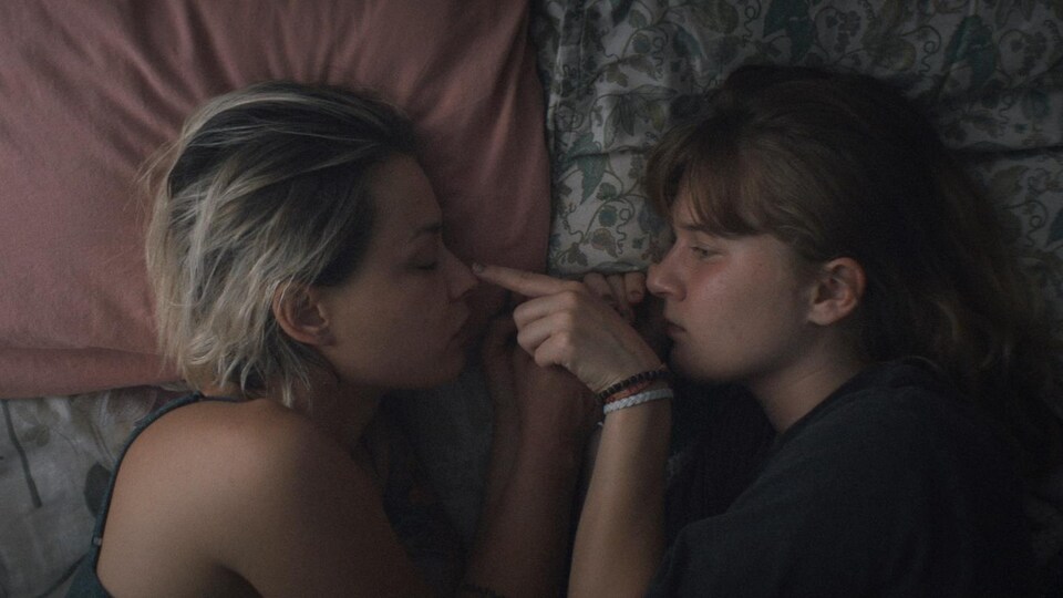 Une mère et sa fille sont face à face dans un lit.