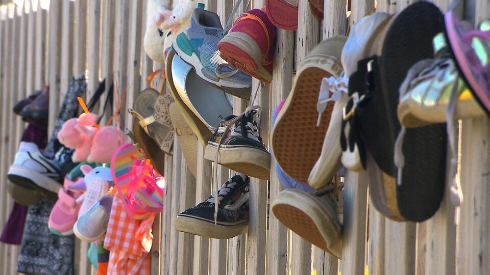 Des souliers d'enfants accrochés à une clôture.