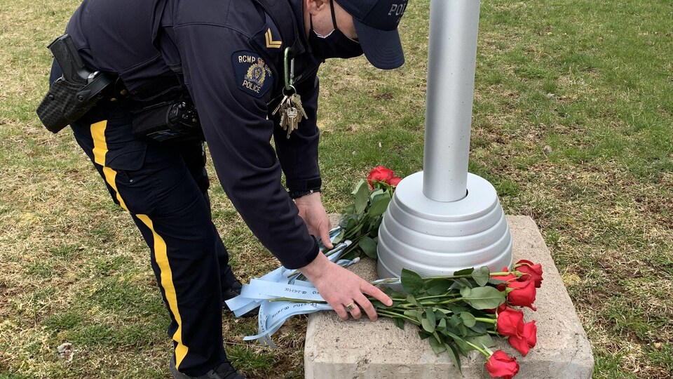 Un gendarme dépose une gerbe de fleurs.