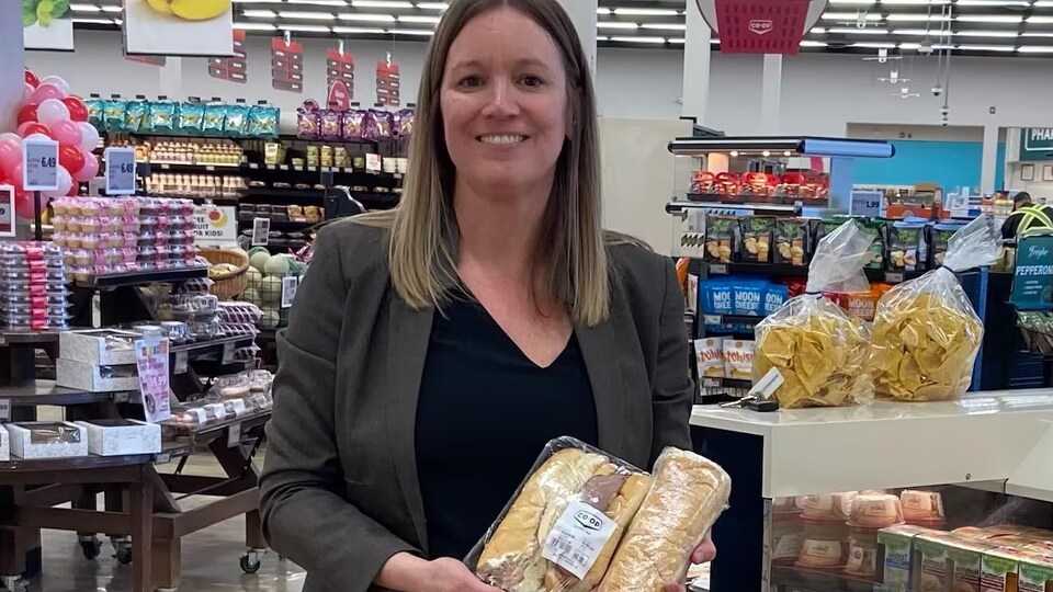 Corrine Kelly-Hyde, la vice-présidente des ressources humaines et de la culture à la Lloydminster and District Co-op tient des sandwichs de charcuterie  en main.