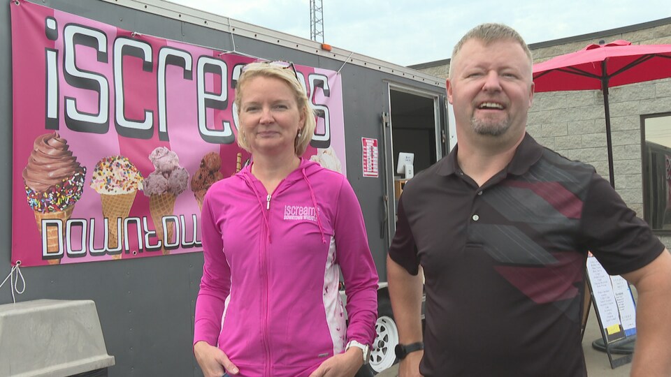 Un couple pose devant leur commerce temporaire