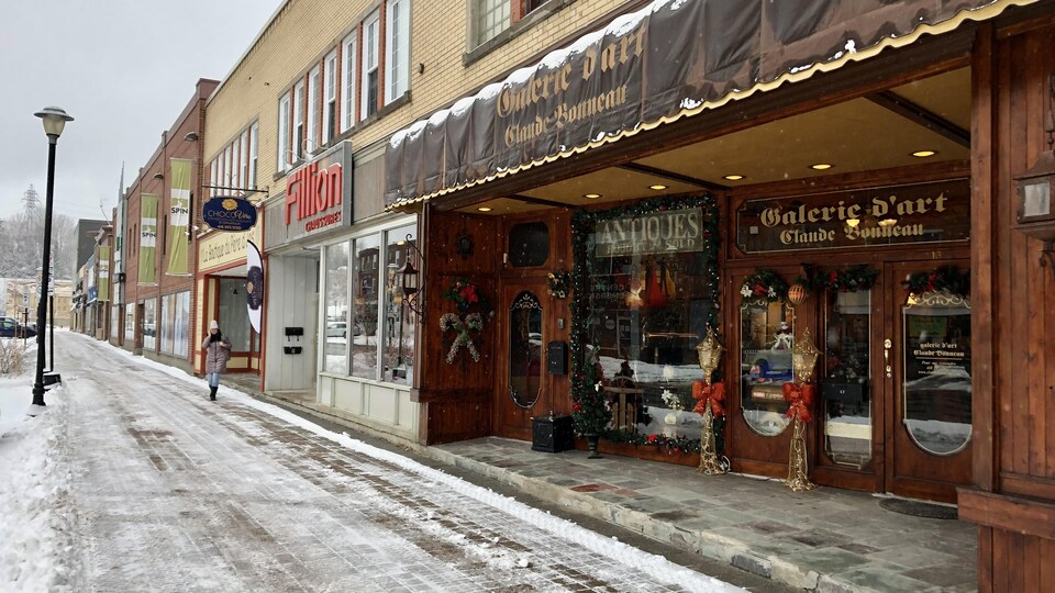 Des façades de commerces vues du trottoir, en hiver, à la place LaSalle à Baie-Comeau.