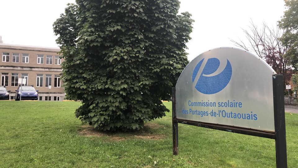 Une affiche portant le logo de la Commission scolaire des Portages-de-l’Outaouais est installée devant une école.