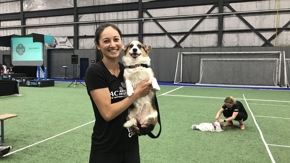 Une personne tient un chien dans ses bras. Elle sourit à la caméra.