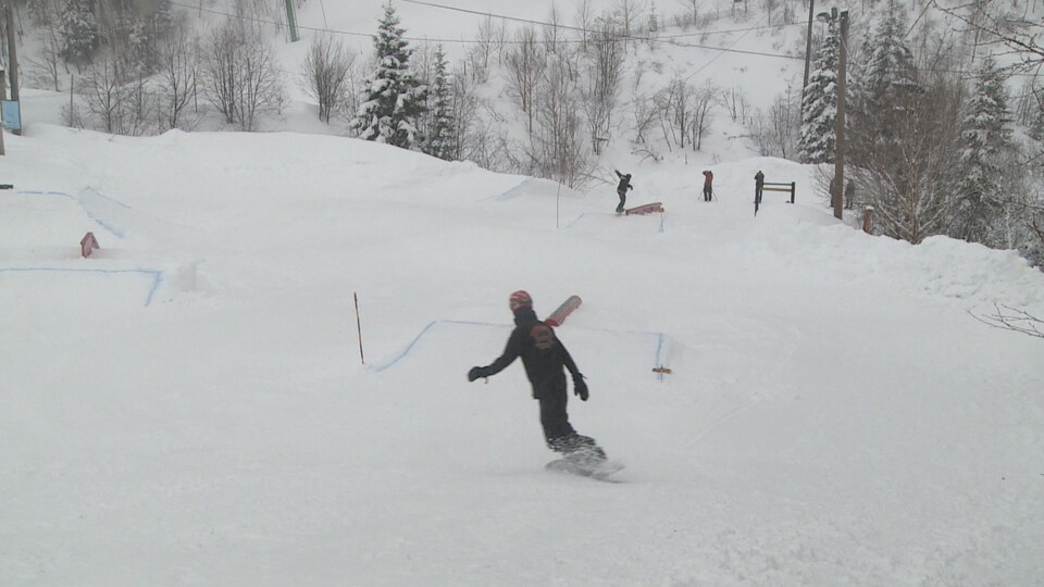 Un skieur sur une planche à neige dévale une piste enneigée.