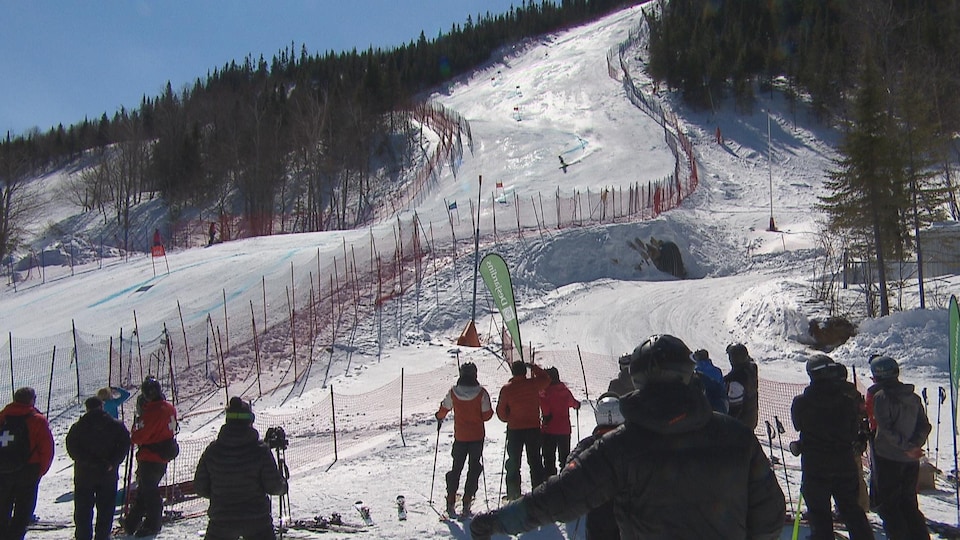Des spectateurs en bordure du parcours emprunté par les skieurs regardent les compétitions.