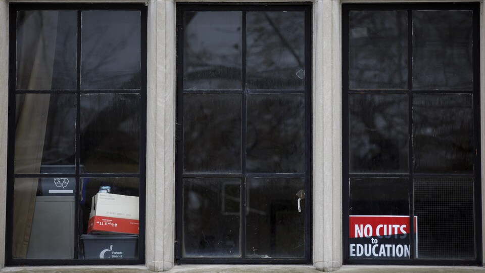 Une pancarte d'opposition aux compressions dans la fenêtre d'une école.
