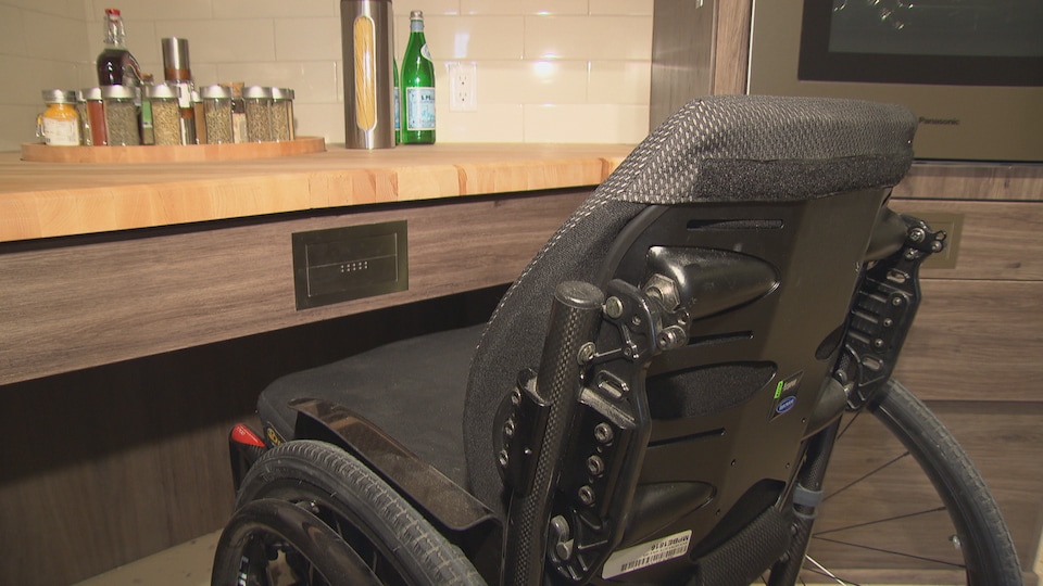 Un fauteuil roulant sous un comptoir de cuisine. 