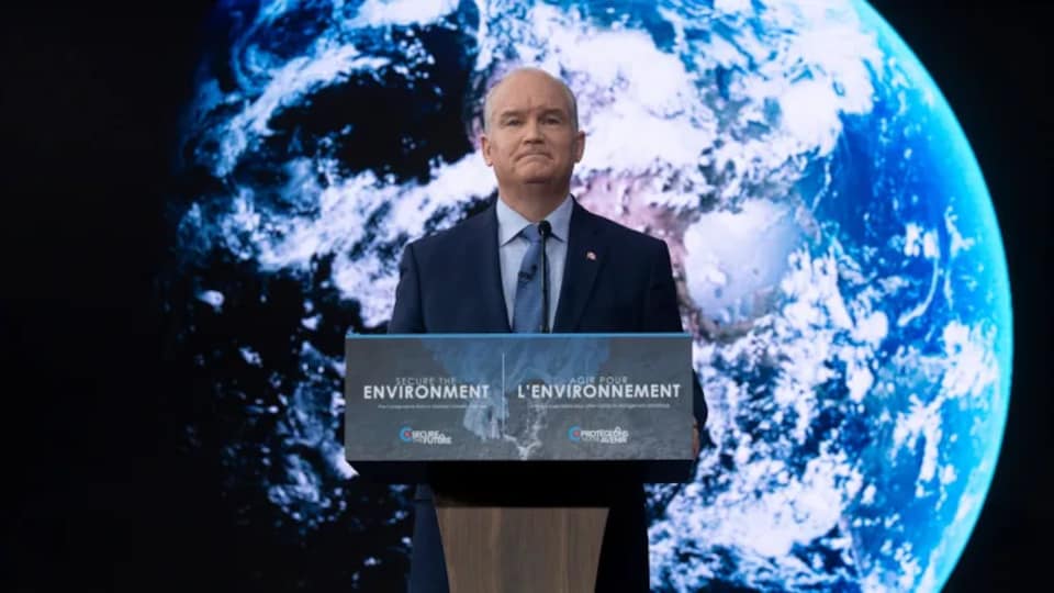 Erin O'Toole in front of a photo of planet Earth.