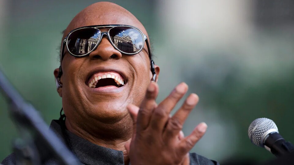 Stevie Wonder sourit devant son micro lors d'un concert