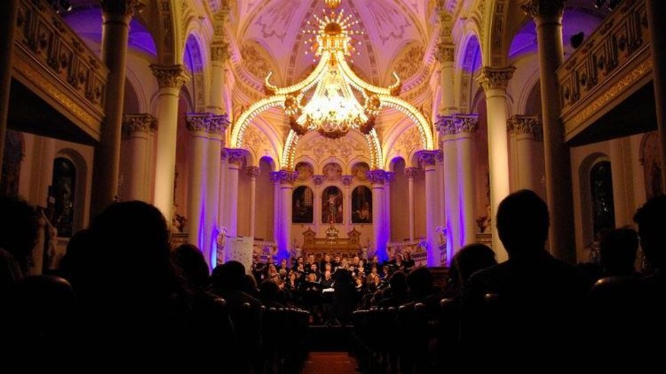 Un choeur illuminé dans l'église, devant une assistance nombreuse.
