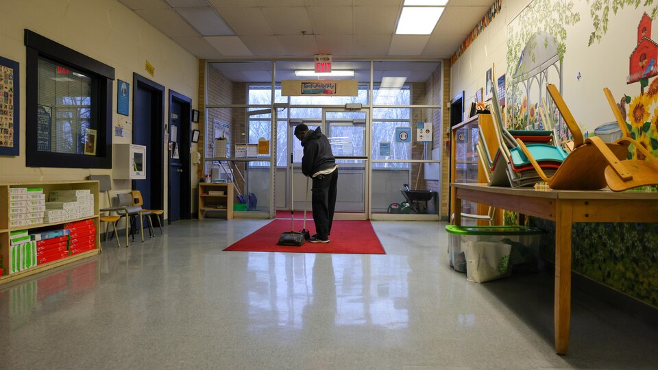 Un concierge nettoie l'entrée d'une école.