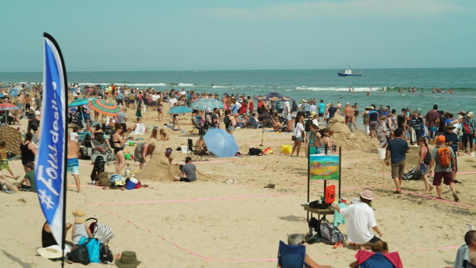 Hundreds of people walk on the sandy beach.
