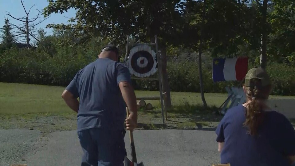 Un homme tenant une hache devant une cible.