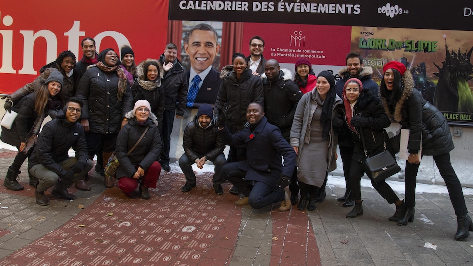 Des gens prennent une photo devant une affiche de Barack Obama.