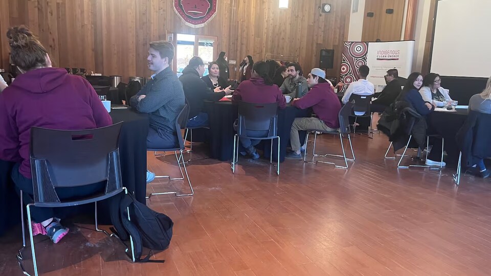 Des jeunes, assis autour de tables, discutent.