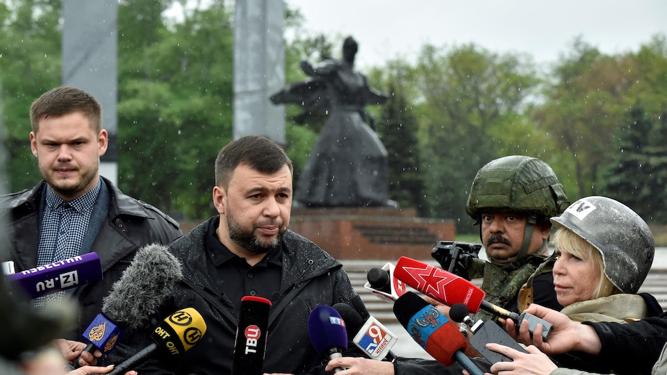 Denis Pouchiline talks to reporters in the rain.